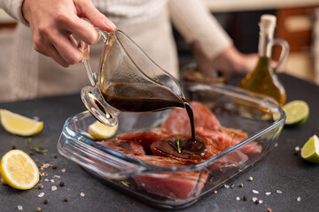 Woman pours soy sauce based marinade into glass cooking dish to marinate Pieces of Fresh tuna Fish...