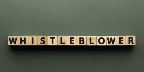 WHISTLEBLOWER word made with building wooden blocks on GRAY background
