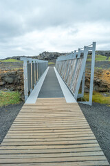 Obraz premium Middle Atlantic Ocean Ridge, bridge between two tectonic plates, Midlina, famous tourist attraction in Iceland with lava field cracks, cliffs and rocks