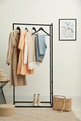 Rack with different stylish women's clothes, boots and bag indoors