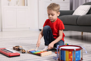 Little boy playing toy xylophone at home