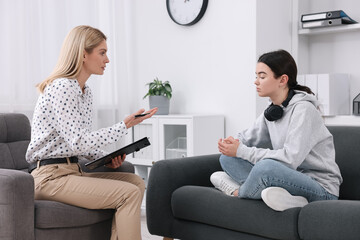 Psychologist working with teenage girl in office - obrazy, fototapety, plakaty