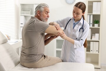 Arthritis symptoms. Doctor examining patient's elbow in hospital