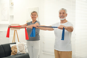 Fototapeta premium Senior couple doing exercise with fitness elastic bands at home