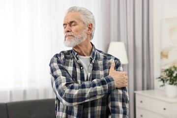 Arthritis symptoms. Man suffering from pain in shoulder at home