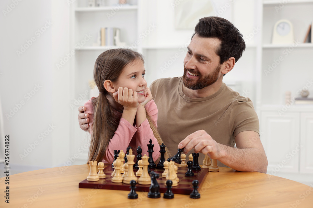 Poster Father teaching his daughter to play chess at home