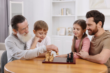Family playing chess together at table in room
