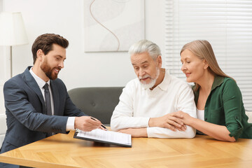 Notary showing senior couple where to sign Last Will and Testament in office
