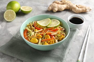 Stir-fry. Delicious cooked noodles with chicken and vegetables in bowl served on gray textured table