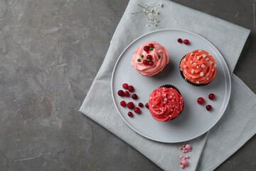 Delicious cupcakes with pink cream and berries on grey table, top view. Space for text