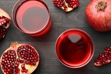 Tasty pomegranate juice in glasses and fresh fruits on black wooden table, flat lay