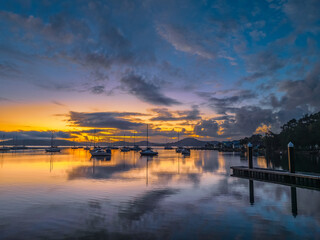 Aerial sunrise waterscape with boats, clouds and fog over the mountain range