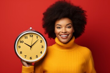 Happy woman in yellow holding a large round clock on a red background