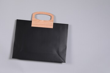 One black paper shopping bag on grey background, top view. Space for text