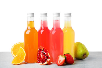 Delicious kombucha in glass bottles and fresh fruits on grey table against white background