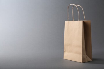 One kraft paper bag on grey background, space for text. Mockup for design