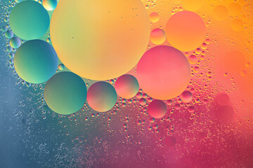 Abstract yellow, green, pink and blue colorful background with oil on water surface. Oil drops in...