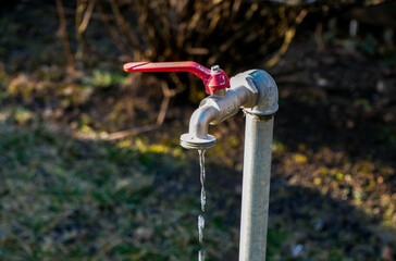 Dripping water from a garden water tap close up shot on a bright sunny day.