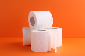 Soft toilet paper rolls on orange background, closeup