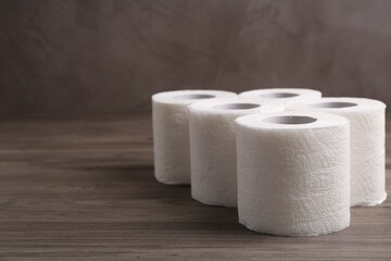 Soft toilet paper rolls on wooden table, closeup. Space for text