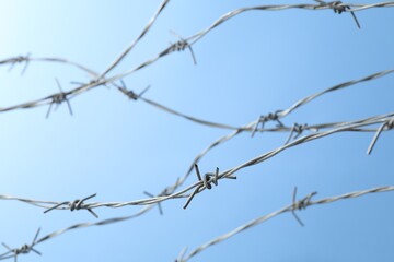 Fototapeta na wymiar Metal barbed wire on light blue background