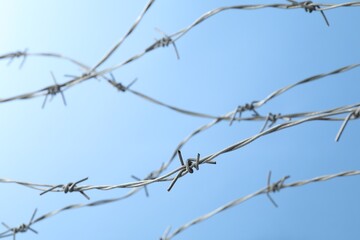 Metal barbed wire on light blue background