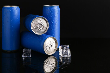 Energy drinks in wet cans and ice cubes on black background, space for text