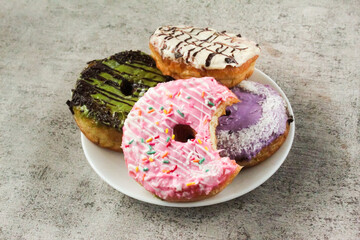 a plate of donuts with several flavors as a snack