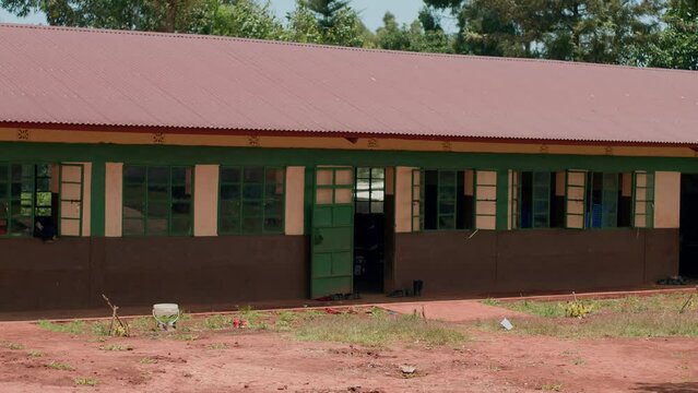 View of one-story african school in kenya building in poor area and silhouettes of children in doorway