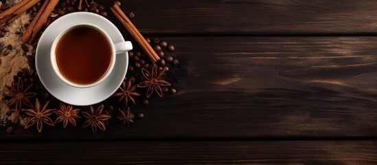 A top view of a wooden table featuring a cup filled with tea surrounded by aromatic cinnamon sticks and star anise. The warm beverage emits a comforting scent, creating a cozy atmosphere.