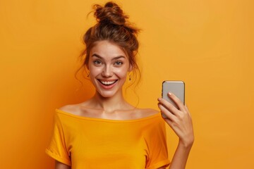Fototapeta premium Joyful young woman with a smartphone on a bright yellow background