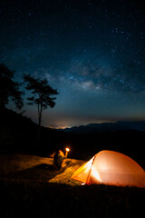 Fototapeta na wymiar nature traveling with orange camping tent on mountain with milky way background