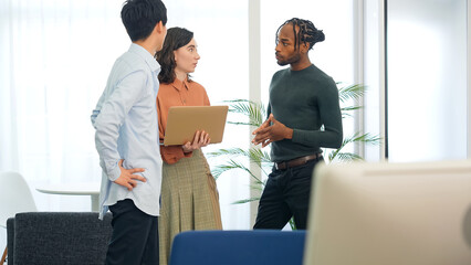 Fototapeta premium Multinational people talking while looking at laptop PC in the lobby. International business.
