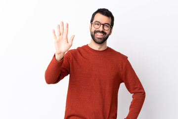 Caucasian handsome man with beard over isolated white background saluting with hand with happy...