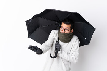 Caucasian handsome man with beard holding an umbrella over isolated white wall