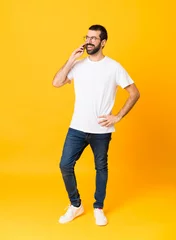  Full-length shot of man with beard over isolated yellow background keeping a conversation with the mobile phone © luismolinero