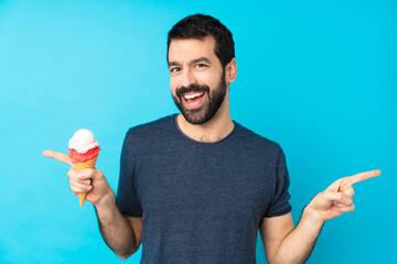 Young man with a cornet ice cream over isolated blue background pointing finger to the laterals and...