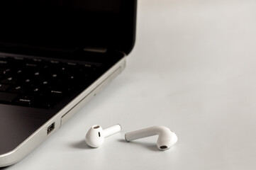 close-up of the laptop and wireless headphones on a light-colored background