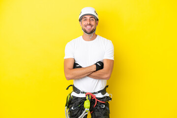 Young rock- climber man isolated on yellow background keeping the arms crossed in frontal position