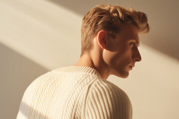 Portrait of a young handsome man in a white sweater. profile shot, minimalistic editorial, elegant realism, chunky knit sweater exquisite details, sunlight. cream and white.