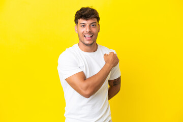 Young caucasian handsome man isolated on yellow background celebrating a victory