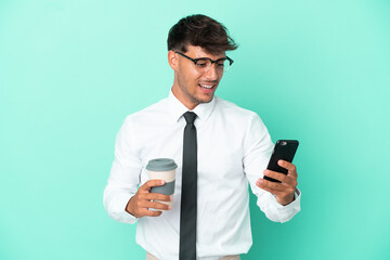 Business caucasian man isolated on blue background holding coffee to take away and a mobile