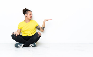 Caucasian man sitting on the floor holding copyspace with doubts