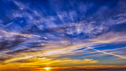 Vivid Sunset Sky With Streaking Clouds Over A Serene Horizon