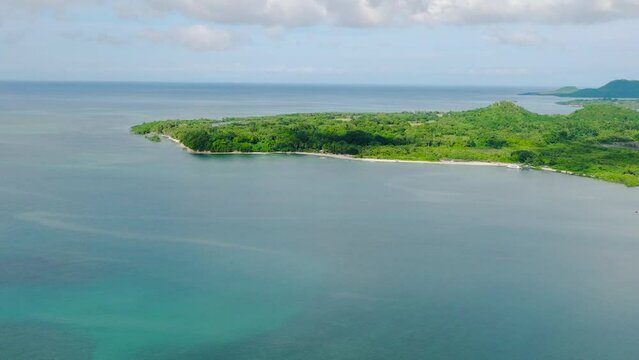Drone view of tropical island with green plants surrounded by turquoise sea water. Looc, Tablas Island. Romblon, Philippines.