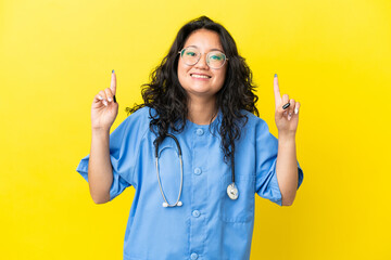 Young surgeon doctor asian woman isolated on yellow background pointing up a great idea