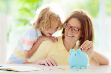 Child putting coin in piggy bank. Kids and money.