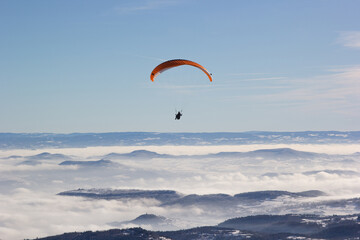 Paragliding. Paragliding in Auvergne. paragliding flight in the mountains in France. Paragliding over the clouds. Sea of clouds and paraglider. Panorama of the mountains. Puy de Dôme. Parapente.