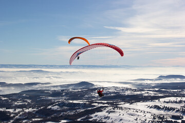 Two paragliders. Paragliding in Auvergne. paragliding flight in the mountains in France. Paragliding over the clouds. Sea of clouds and paraglider. Panorama of the mountains. Puy de Dôme. Parapentes. 