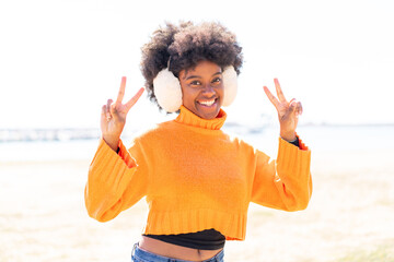 African American girl wearing winter muffs at outdoors showing victory sign with both hands